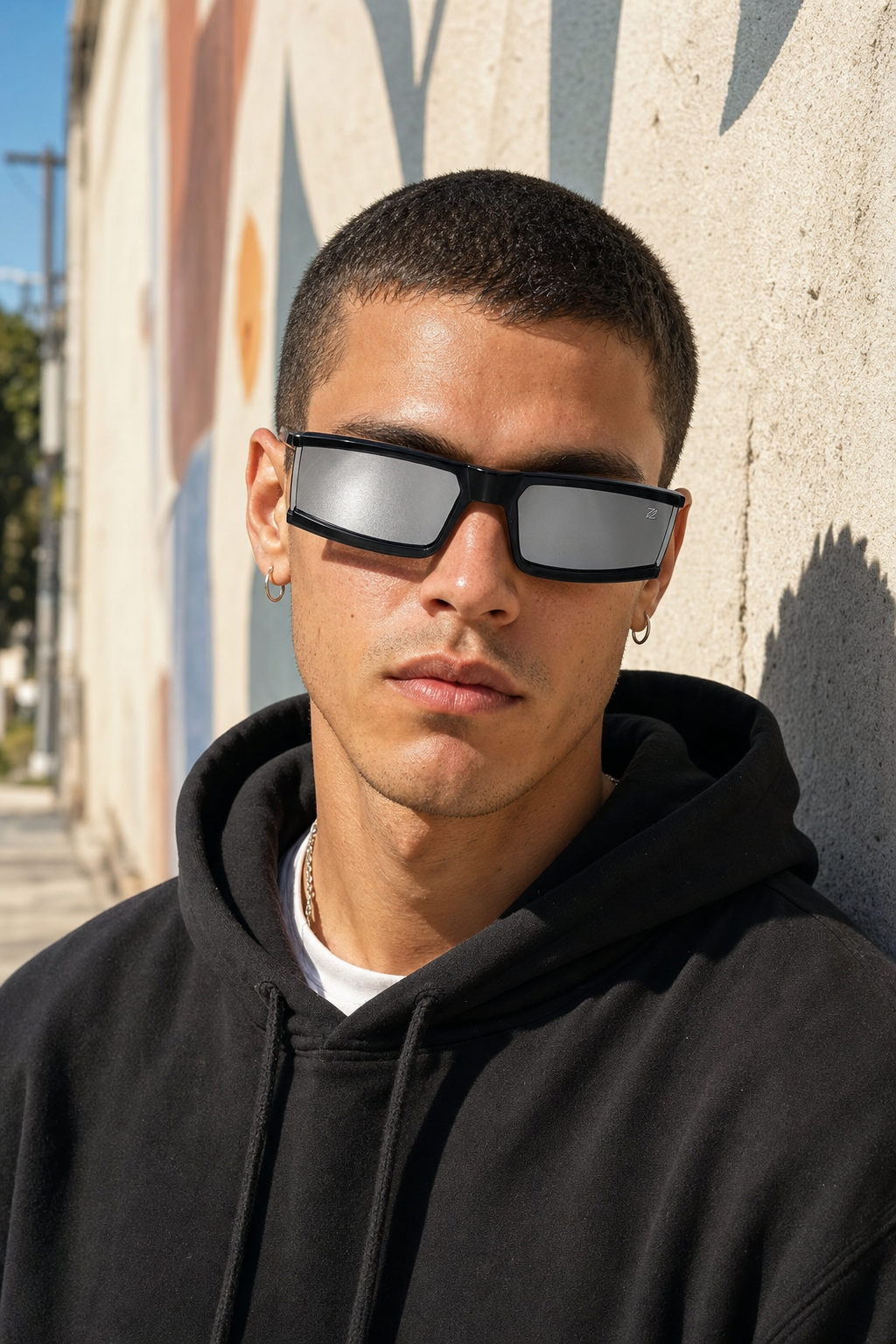 Model wearing PHANTOM sunglasses in black frame with mirrored lenses against a stucco wall in LA